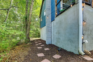A pathway leading to a house with a blue exterior and brick foundation, surrounded by a forested area. - Cozy Candler Cottage, Near Hiking and Wildlife (Candler)