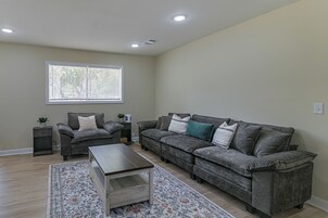 A living room with a sofa, a coffee table, a side table, and a window with blinds.