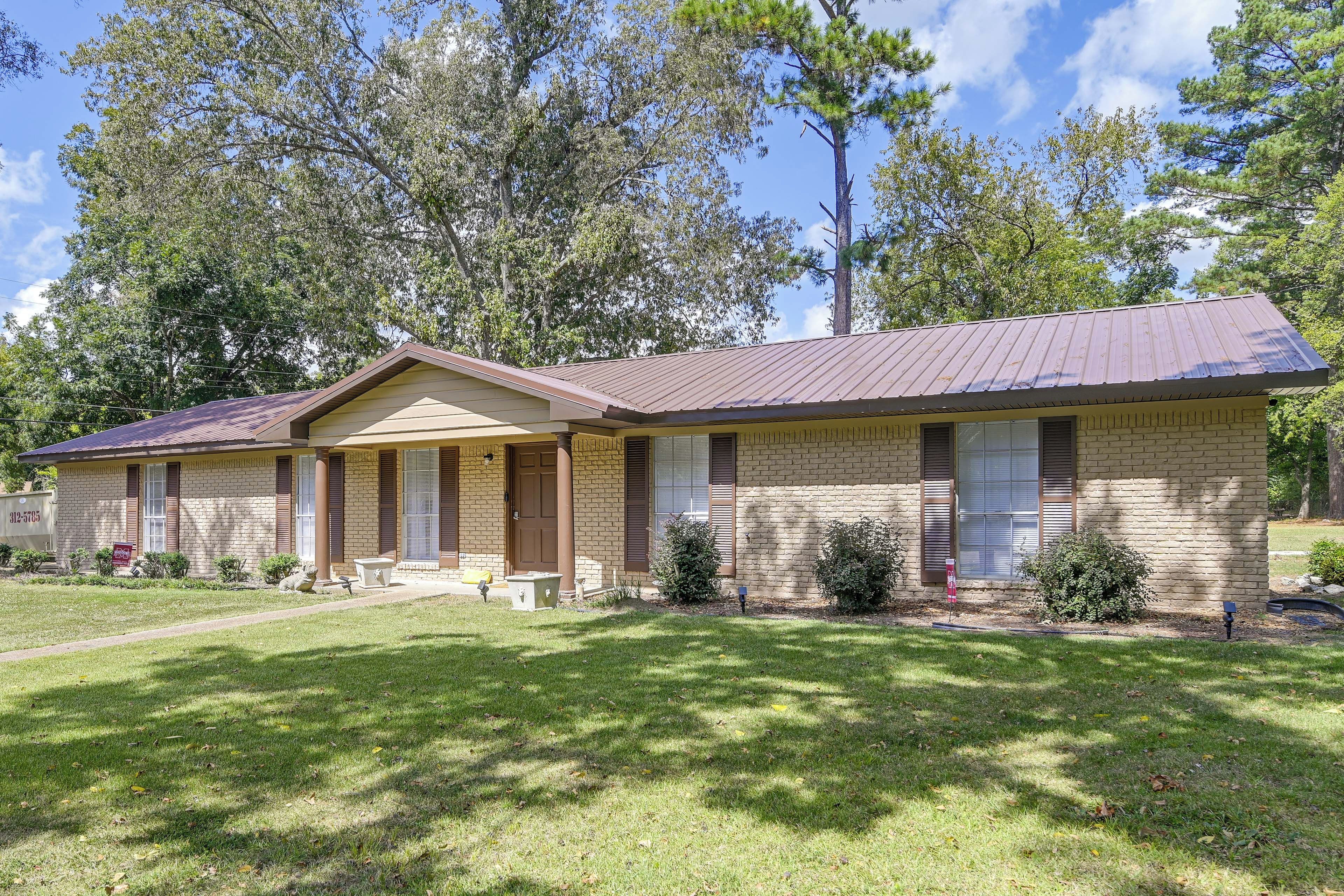 A two-story brick house with a front porch, a garage, and a well-maintained lawn.