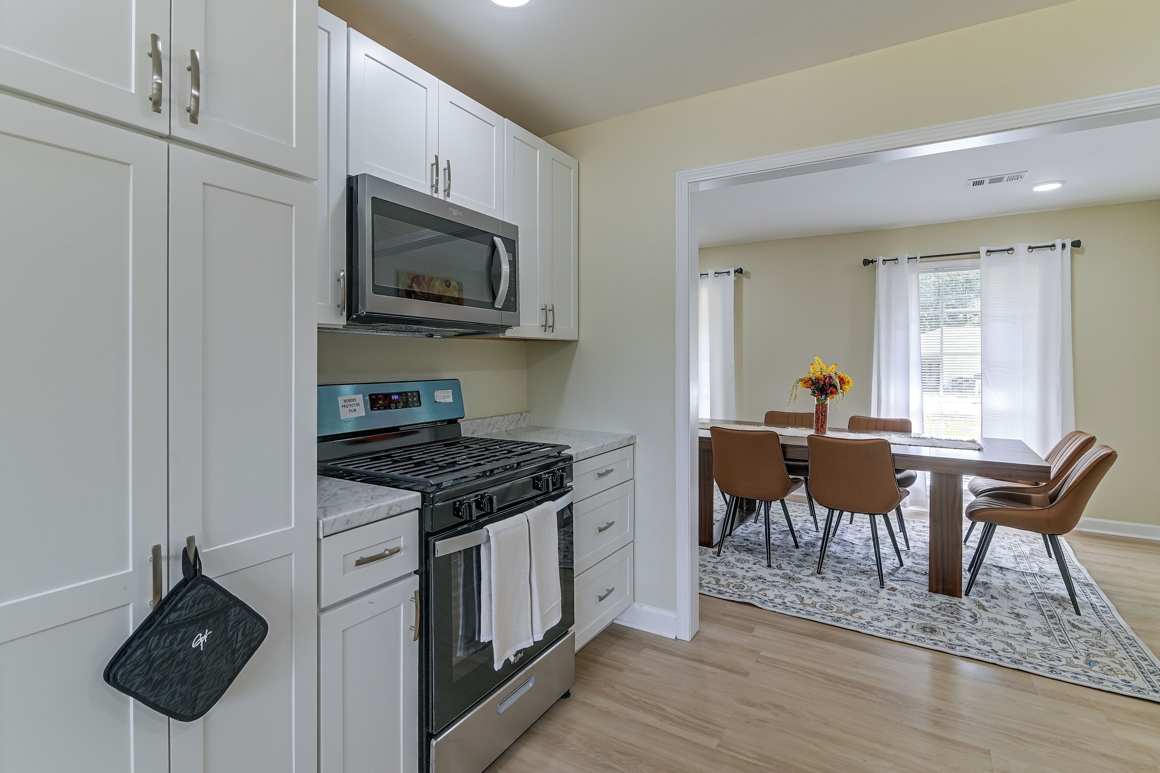 A modern kitchen with white cabinetry, a built-in microwave, and a gas stove.
