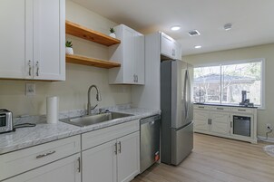 A modern kitchen with white cabinets, a stainless steel refrigerator, and a window providing natural light.