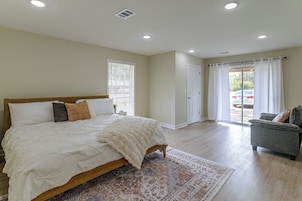 A bedroom with a bed, a window with blinds, a door, and a view of the outside.
