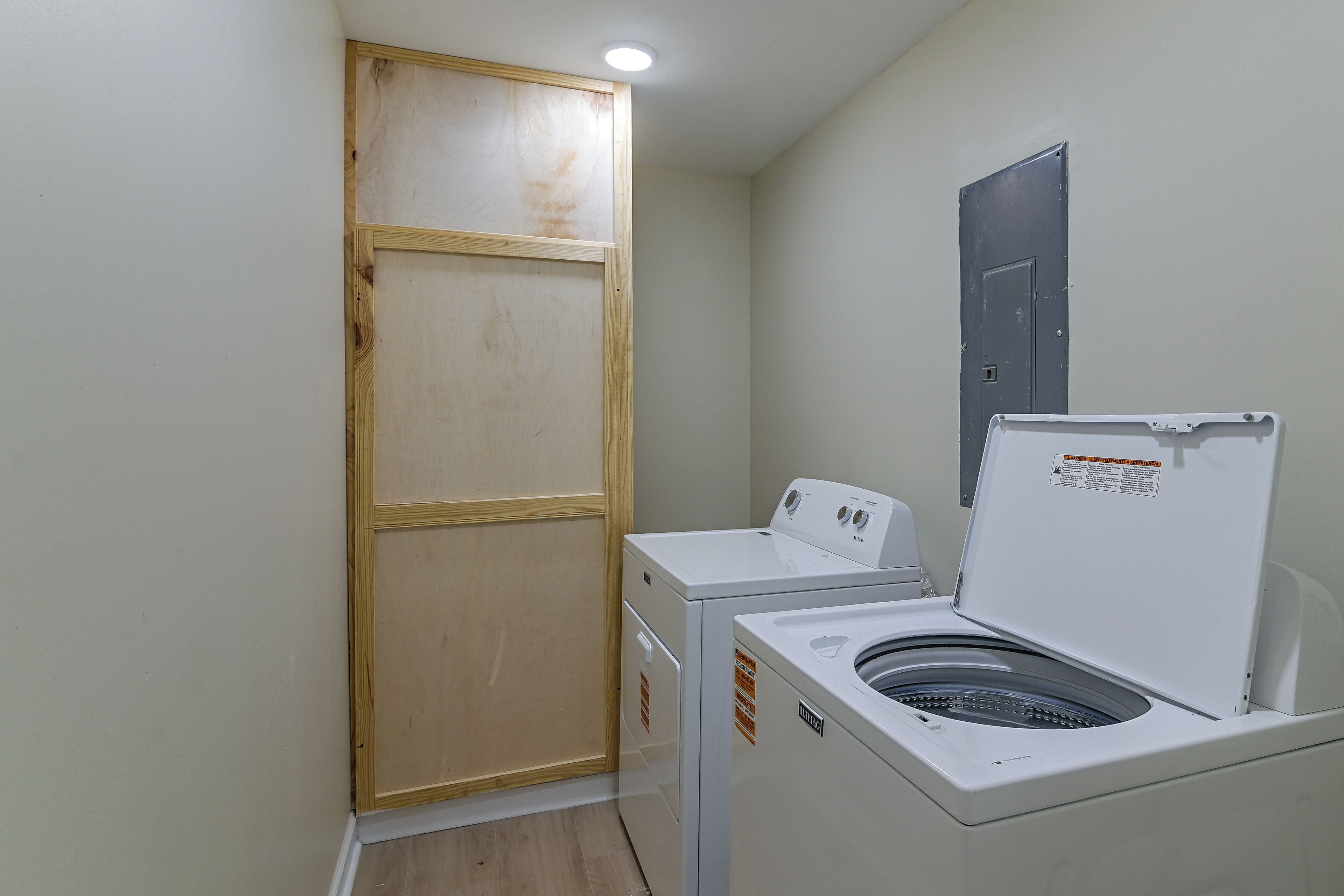 Un cuarto de lavandería con una puerta de madera, una lavadora y una secadora.