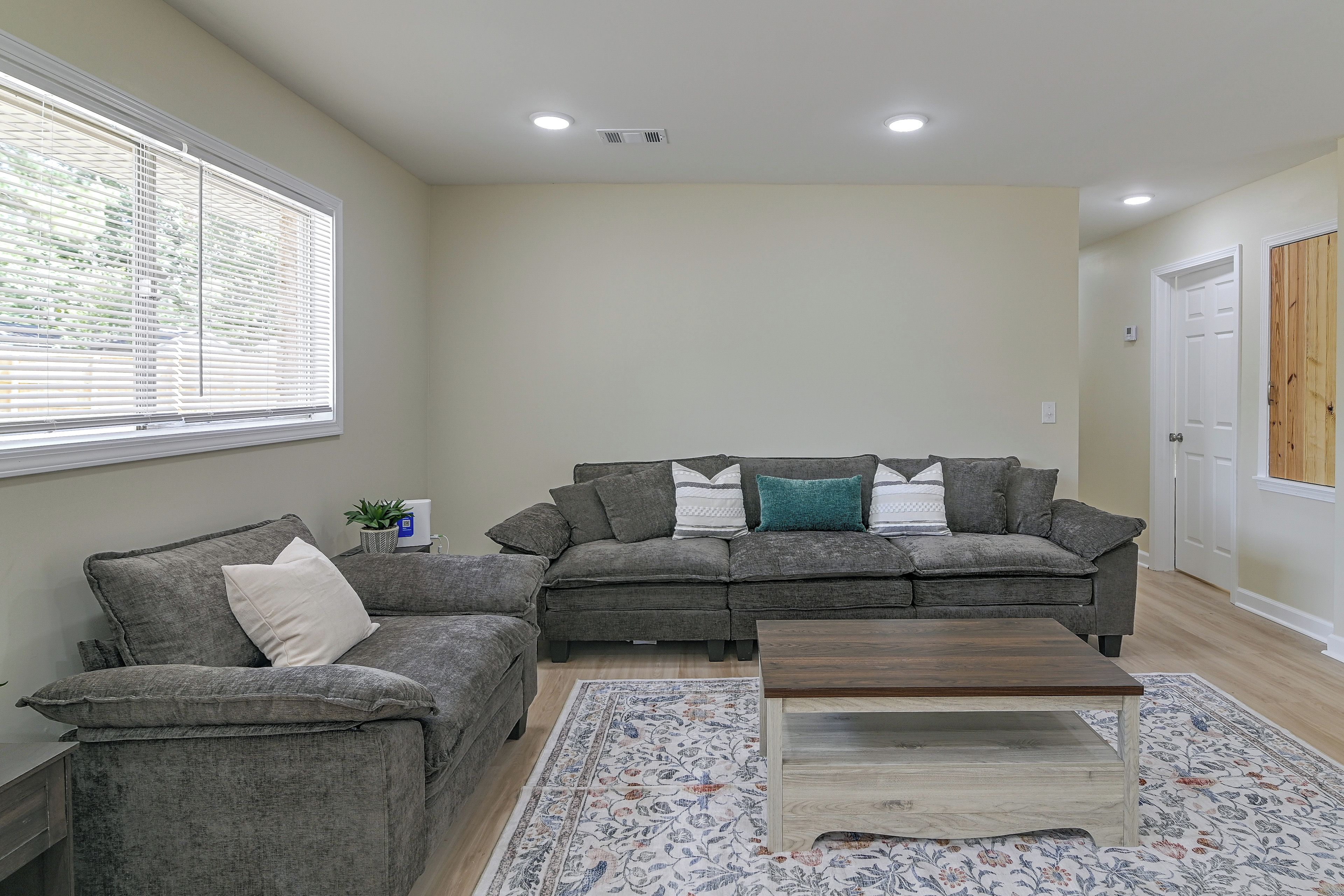 A living room with two grey sofas, a coffee table, and a patterned rug.