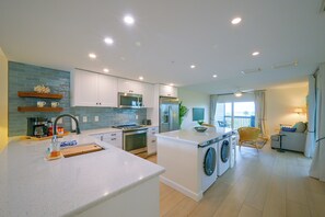 A modern kitchen with white cabinets, a built-in microwave, and a central island with a sink. - Closest Unit to Beach on Little Gasparilla Island (Placida)