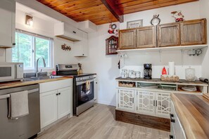 A kitchen with a built-in oven, a microwave, and a sink. There are wooden cabinets and a wooden ceiling. - 'La Massaria' Country Chalet w/ Fall Foliage Views (Ossipee)
