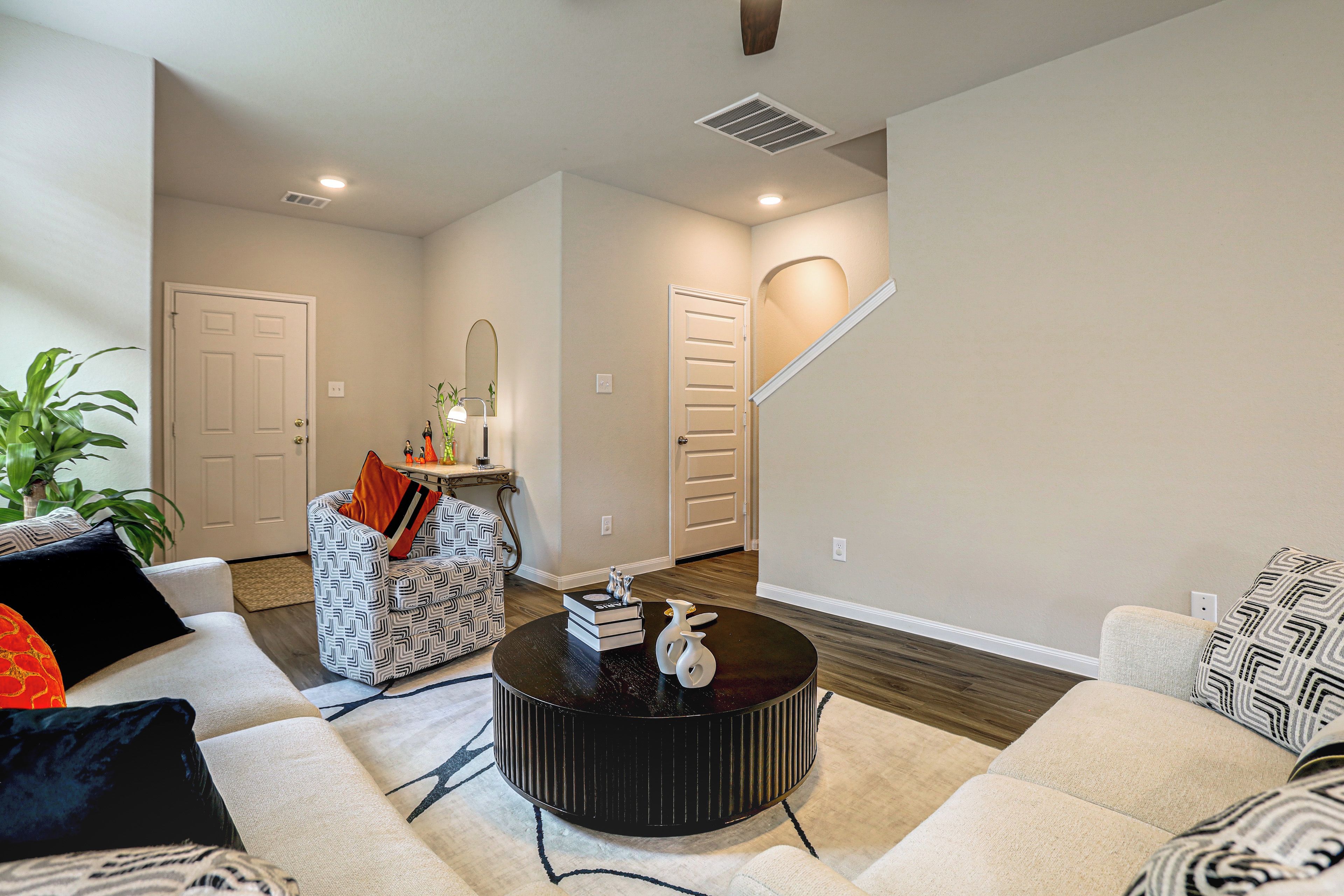 A living room with a sofa, a coffee table, a staircase, and a door.