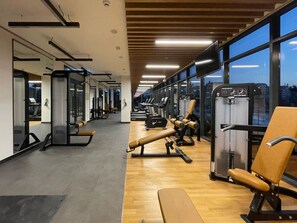 A gym with exercise equipment, mirrors, and large windows. - FIRST CLASS |1BR| Luxury Near Dubai Hills Mall (Dubai Hills)