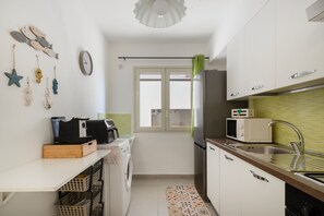 A compact kitchen with a microwave, sink, and a window. - Apartment 'Granchio Blu Porto Palo di Menfi' with sea view and Wi-Fi (Porto Palo Est)