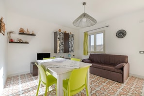 Un espacio habitable compacto con una mesa de comedor, sillas, un sofá y una ventana.