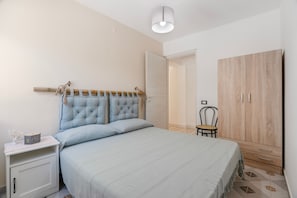 Un dormitorio con cama, mesita de noche, armario y una silla.