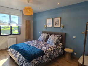 Een slaapkamer met een bed, een raam, een radiator, een nachtkastje en een hanglamp.