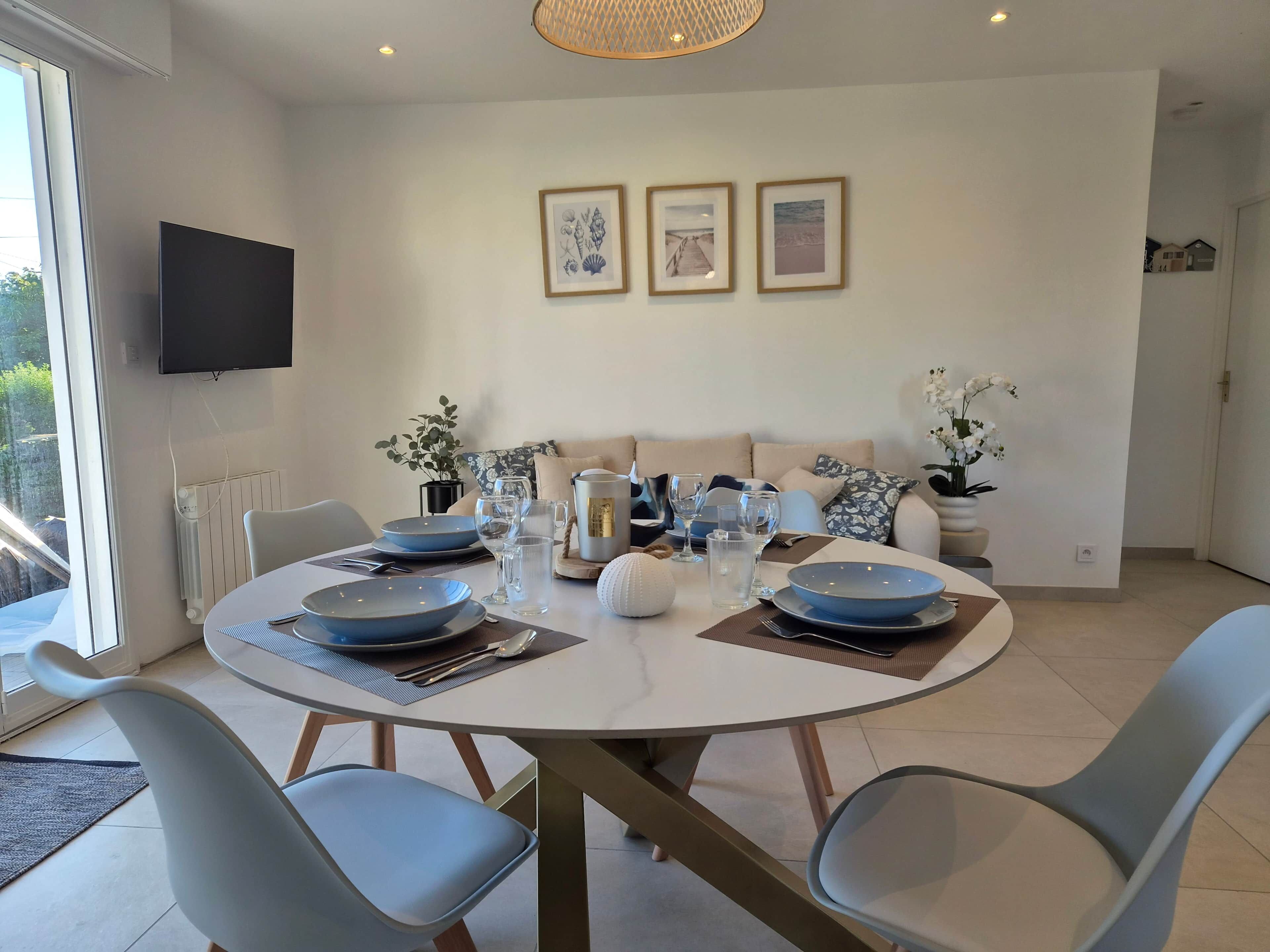 Un espace repas comprenant une table ronde, des chaises et un téléviseur fixé au mur.