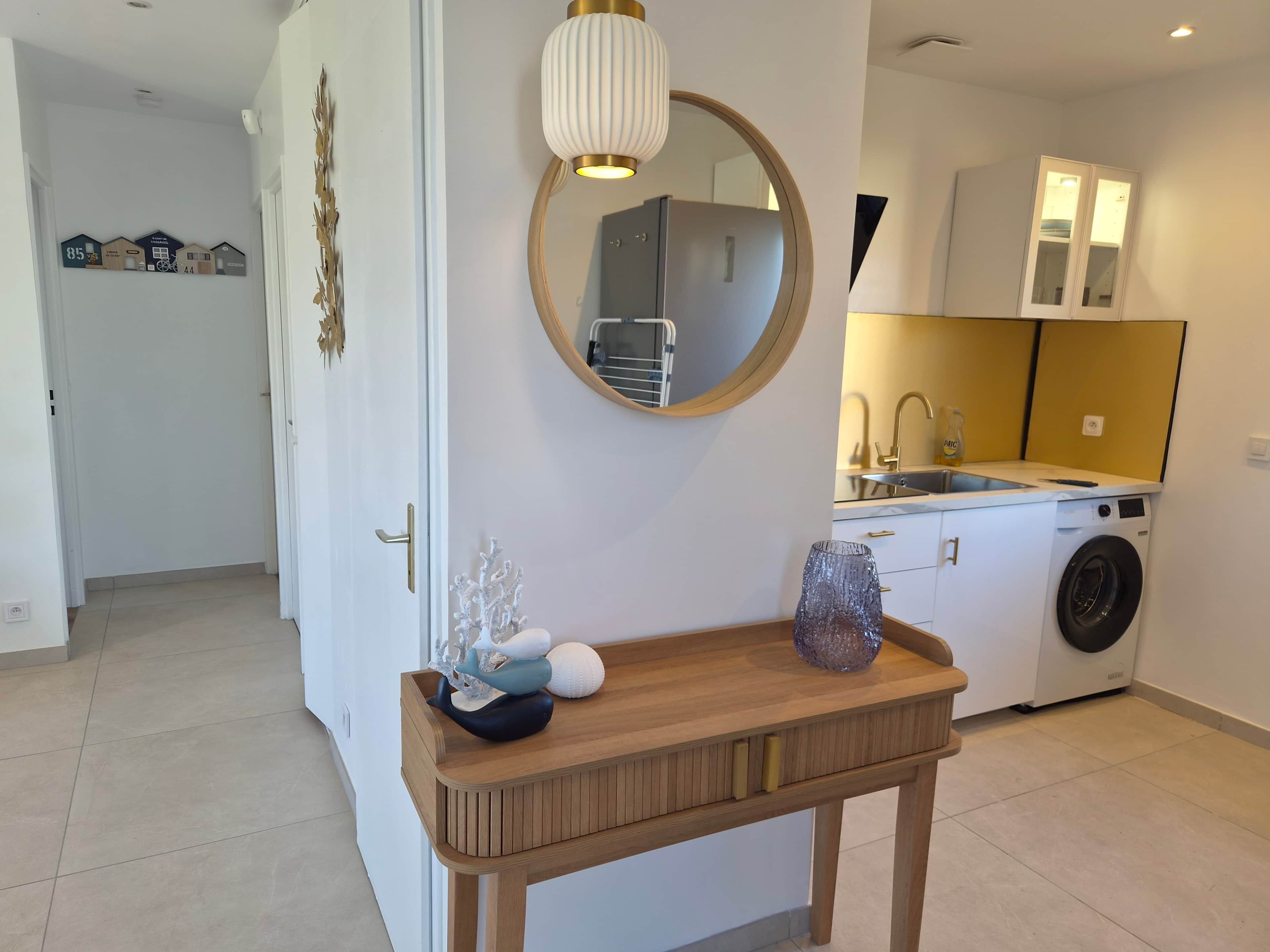 Una cocina moderna con lavadora, un lavabo y un espejo sobre la encimera.