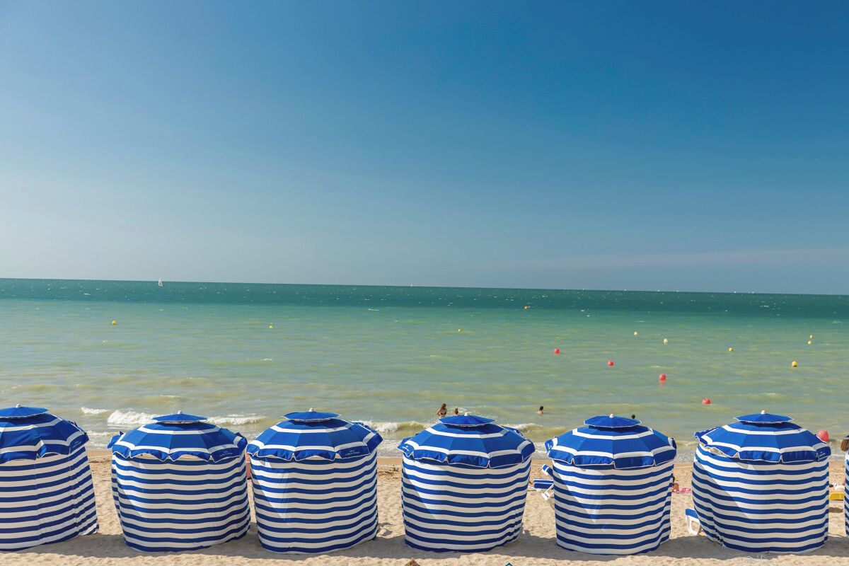 A beach with striped beach umbrellas and a clear blue sky.