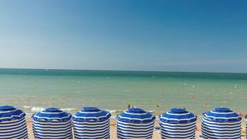 A beach with striped beach umbrellas and a clear blue sky.