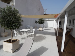 An outdoor patio area with a table and chairs, potted plants, and a wooden deck.