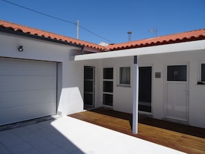 A modern building with a white exterior, a red-tiled roof, and a garage door.