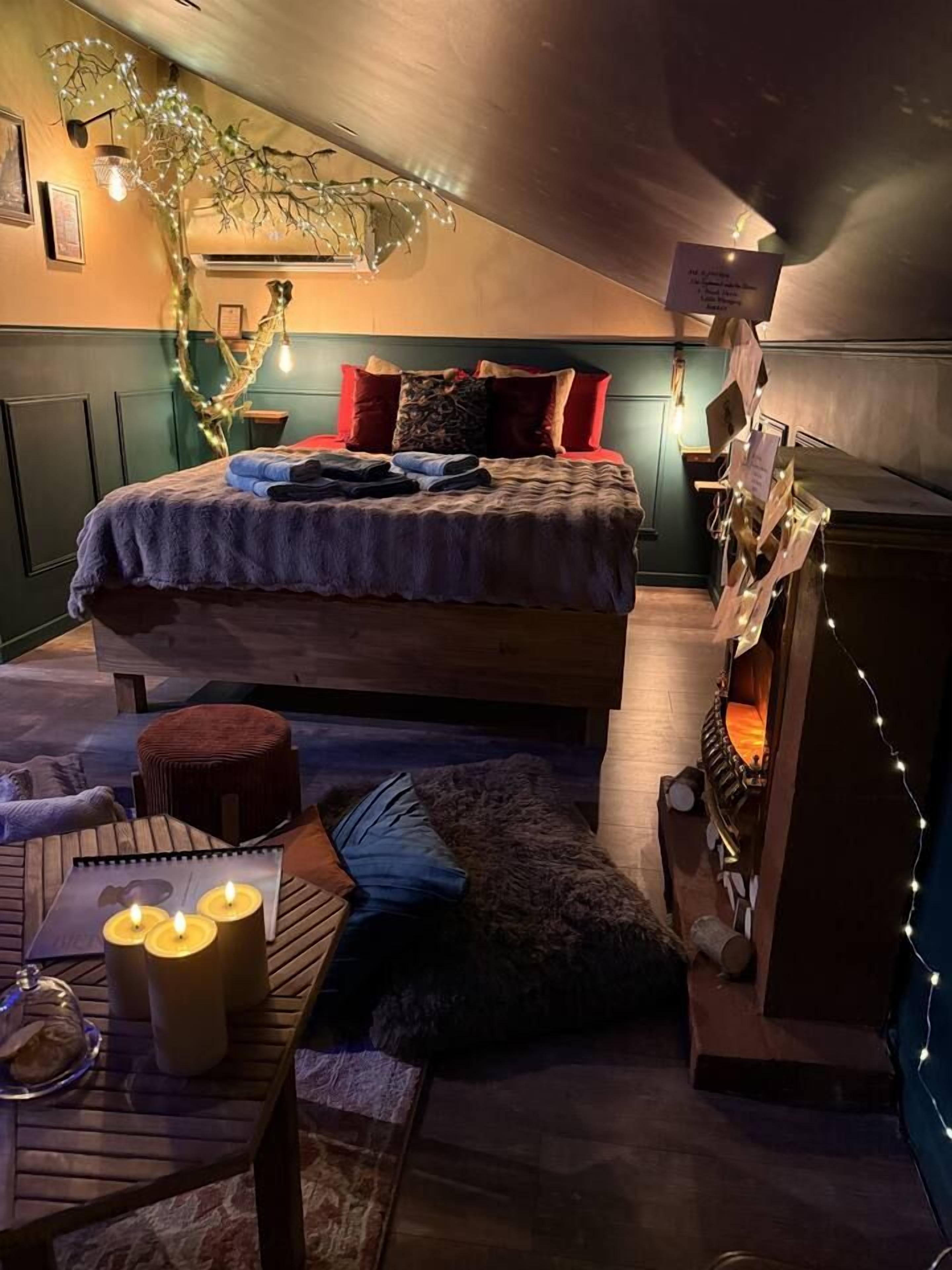 Een gezellige kamer met een bed, een klein tafeltje met kaarsen en een open haard.