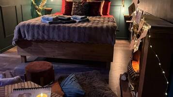 Een gezellige kamer met een bed, een klein tafeltje met kaarsen en een open haard.
