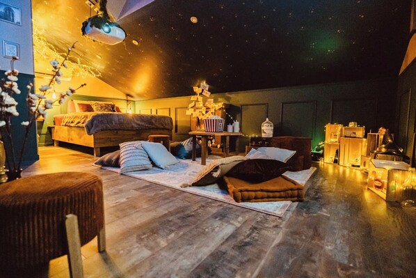 A cozy room with a bed, a small table, and a starry ceiling.