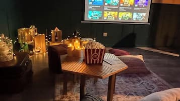 Une pièce chaleureuse avec une table en bois, du pop-corn et un écran de projection affichant une sélection de films.