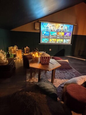 A cozy room with a wooden table, popcorn, and a projector screen displaying movie options.