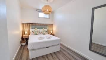 Une chambre à coucher moderne avec un lit, des lampes de chevet, un luminaire suspendu et un grand miroir.