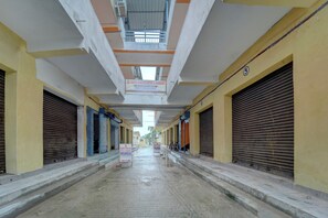 Un pasillo con persianas cerradas, un cartel que indica Hotel & Banquet Siddhi Vinayak y piso mojado.