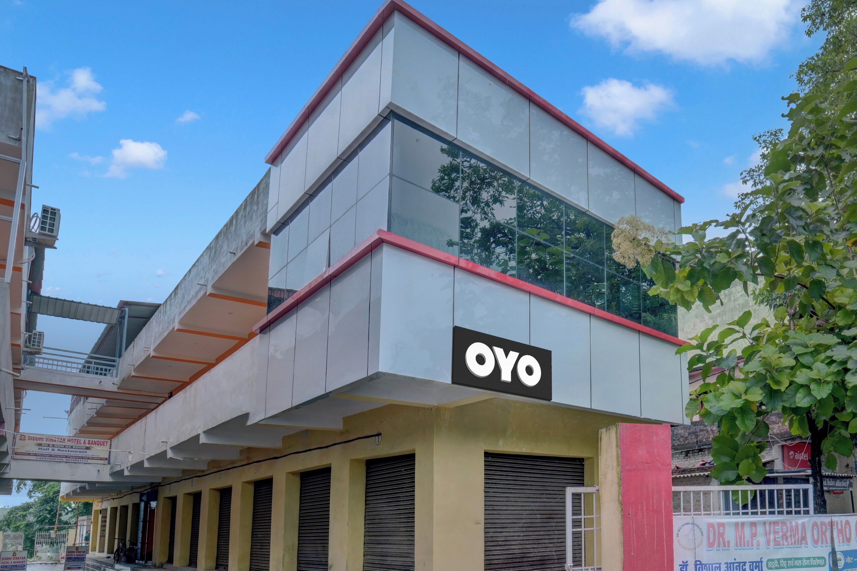 Un edificio con un evidente cartello 'OYO' sulla facciata, caratterizzato da uno stile architettonico moderno con tetto piatto e ampie finestre.