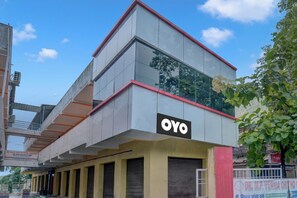Un edificio con un llamativo letrero 'OYO' en la fachada, de estilo arquitectónico moderno con techo plano y grandes ventanales.