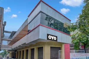 Un edificio con un llamativo letrero 'OYO' en la fachada, de estilo arquitectónico moderno con techo plano y grandes ventanales.