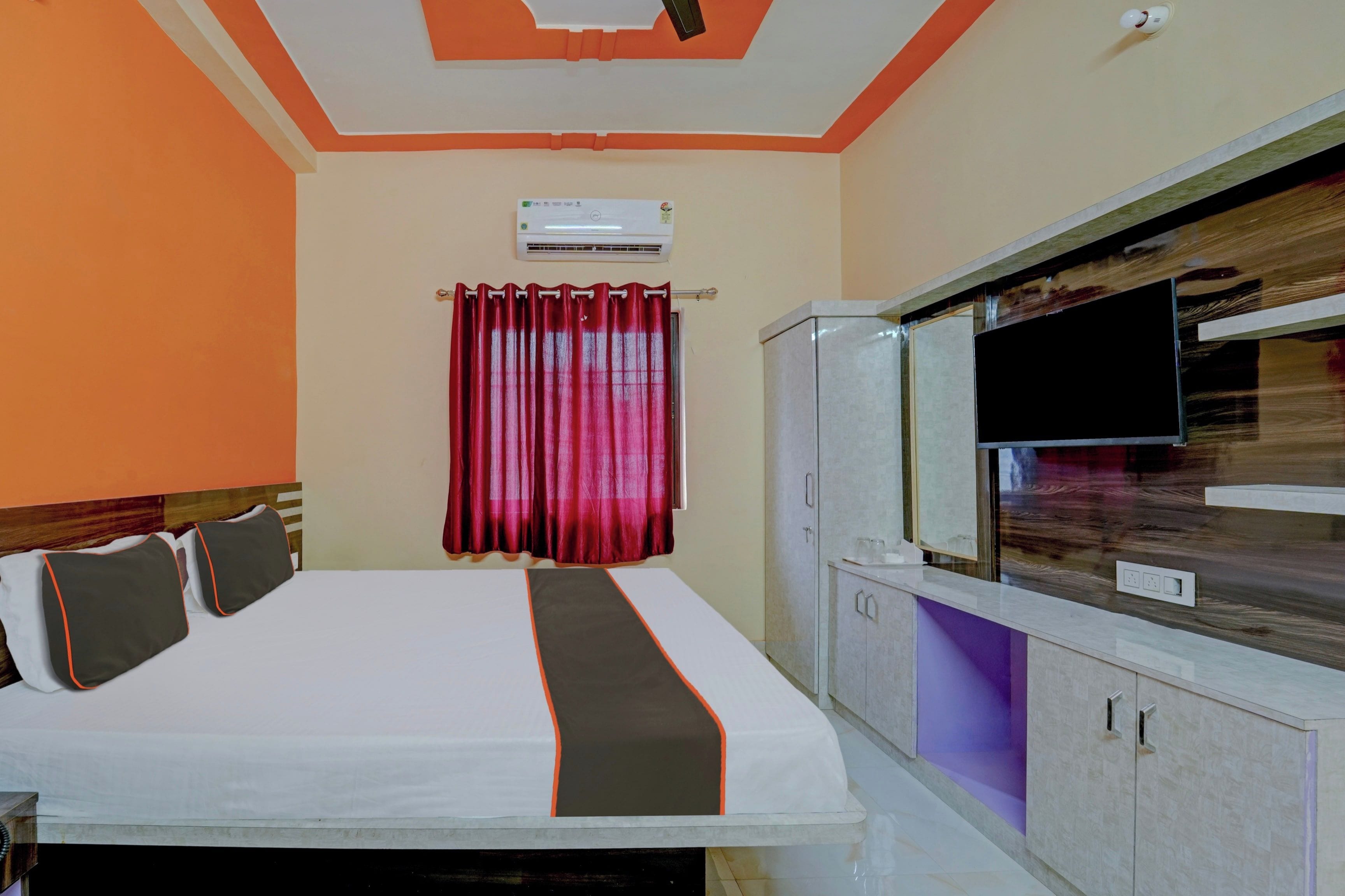 Une chambre d’hôtel avec un lit, une télévision, une armoire et un rideau.