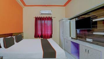 Une chambre d’hôtel avec un lit, une télévision, une armoire et un rideau.