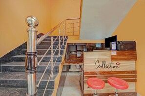 Una escalera con barandilla de metal y un mostrador de recepción de madera con un cartel que dice 'Collection'.