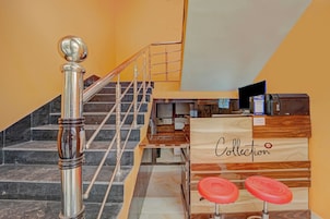 Una escalera con barandilla de metal y un mostrador de recepción de madera con un cartel que dice 'Collection'.