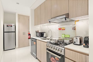 A modern kitchen with a stainless steel refrigerator, a built-in oven, a gas stove, and a microwave. - FIRST CLASS | Studio | Modern City Retreat (Ras Al-Khaimah)