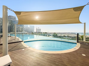 A rooftop swimming pool with a view of the city skyline and the sea. - FIRST CLASS | Studio | Modern City Retreat (Ras Al-Khaimah)