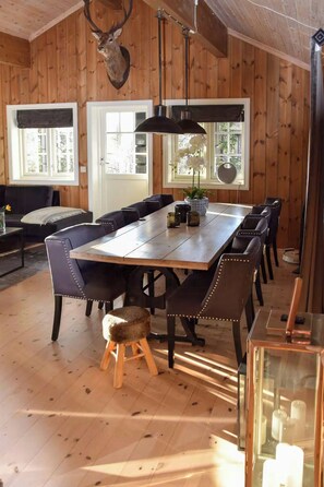 A wooden-paneled dining room with a large table and chairs, a mounted deer head, and a hanging light fixture. - Cabin 50m from cross-country trail on Tempelseter (Eggedal)