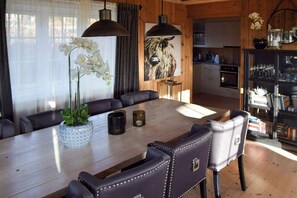 A dining area with a wooden table, leather chairs, and a vase with white flowers. - Cabin 50m from cross-country trail on Tempelseter (Eggedal)