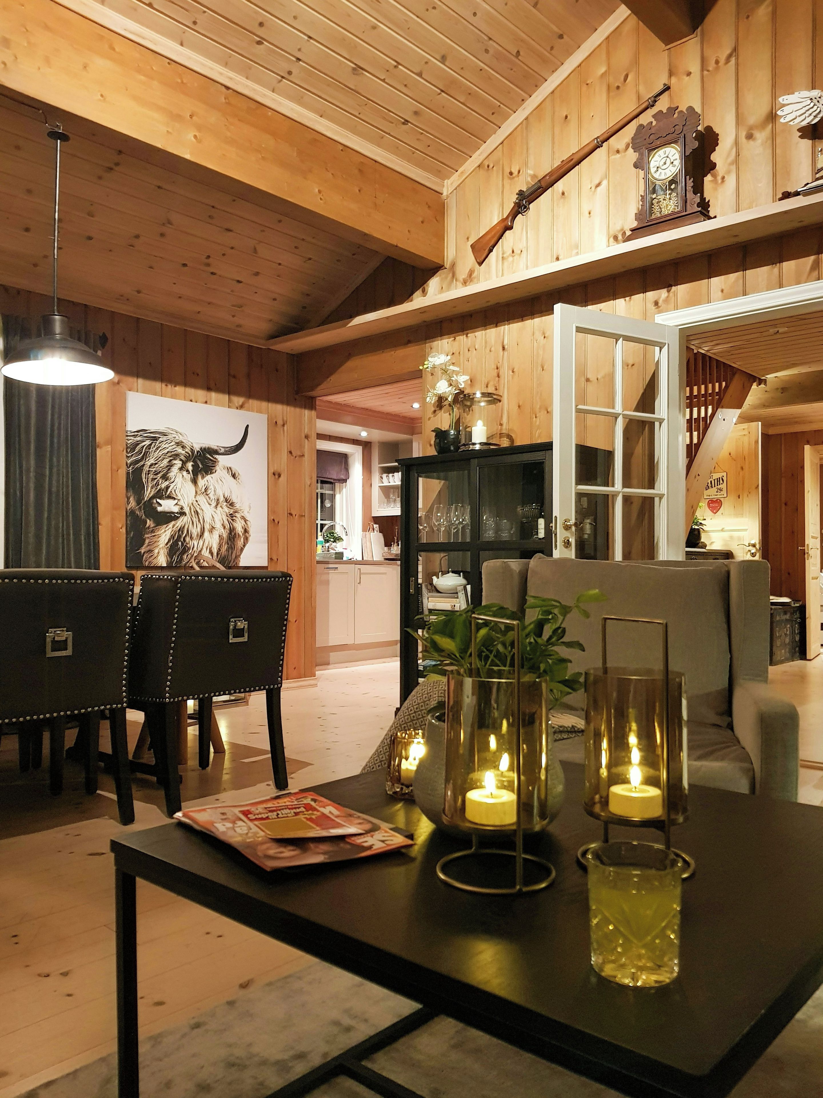 Een houten interieur met een eettafel, stoelen, een bank en een trap.