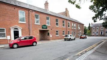 A red car parked in front of a brick building with a sign reading 'Larchfield House.'