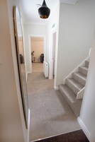 A hallway with carpeted stairs leading to a room, a white door, and a small table with a plant.