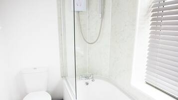 Un baño con una bañera blanca, un inodoro y una ducha.