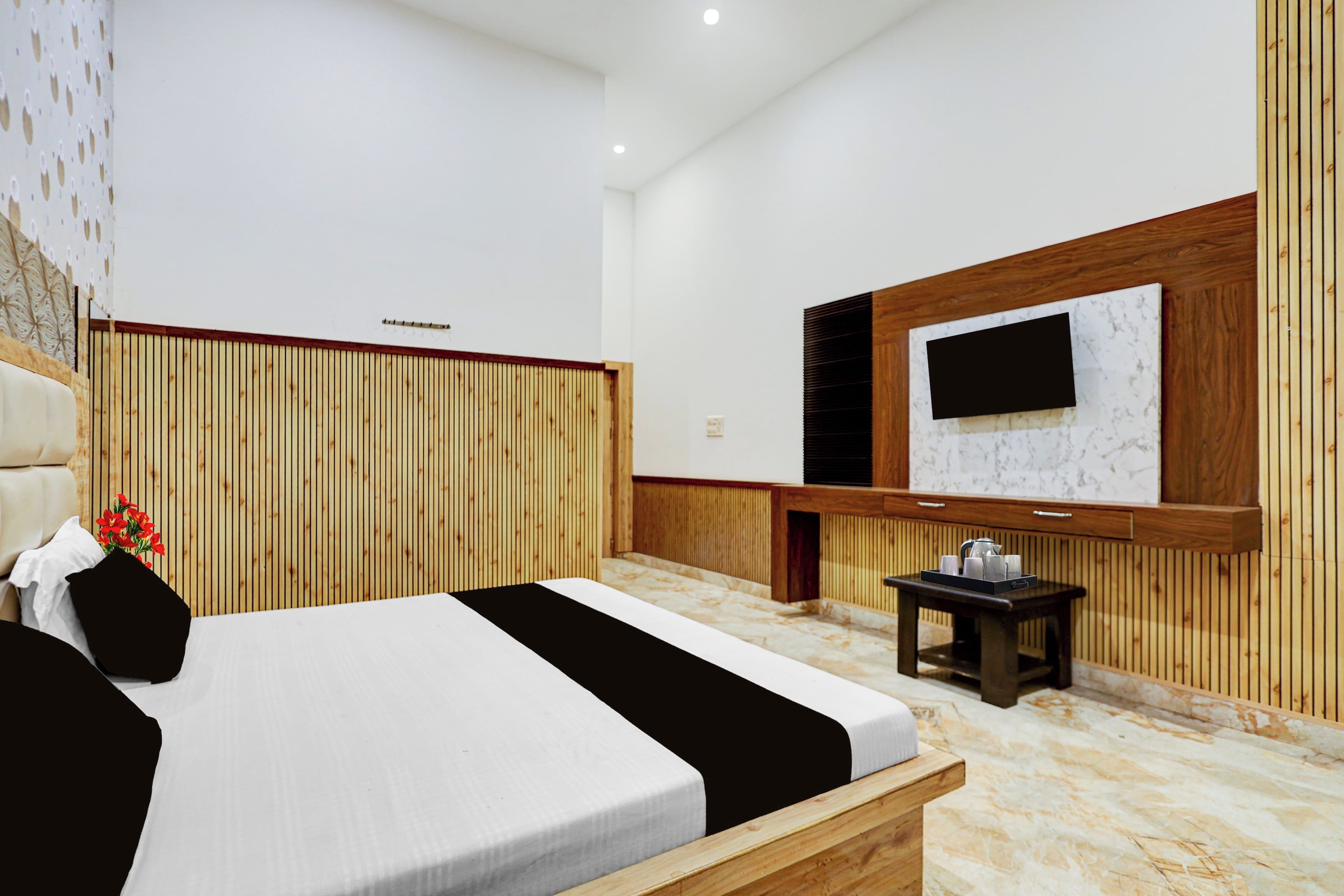 Una habitación de hotel moderna con una cama grande, una mesita con una bandeja, un televisor de pantalla plana en la pared y paneles de madera en las paredes.