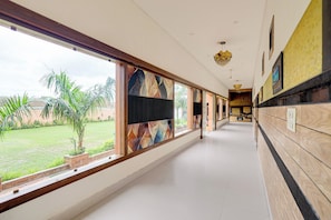 A corridor with large windows, a tiled floor, and a view of a garden.