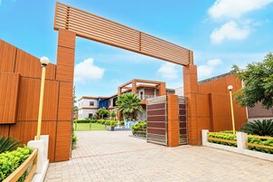 Una entrada moderna a un edificio con un arco de madera, un sendero empedrado y un jardín ajardinado.
