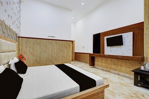 Una habitación de hotel moderna con una cama grande, paneles de madera, un televisor de pantalla plana y una pequeña mesa con una tetera.