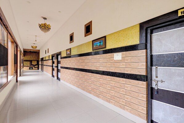 A hotel corridor with a tiled floor, a reception desk, and a door with a number sign.