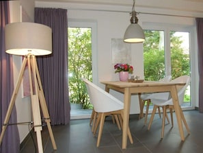 Ein Essbereich mit Tisch, Stühlen, einer Stehlampe und Blick auf Grünfläche.